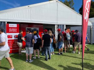 Motor enhusiasts crowd watching live demo of SPEE3D printer